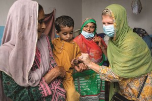 Jennifer interage com uma criança após vaciná-la contra a pólio numa casa em Karachi, no Paquistão, em agosto